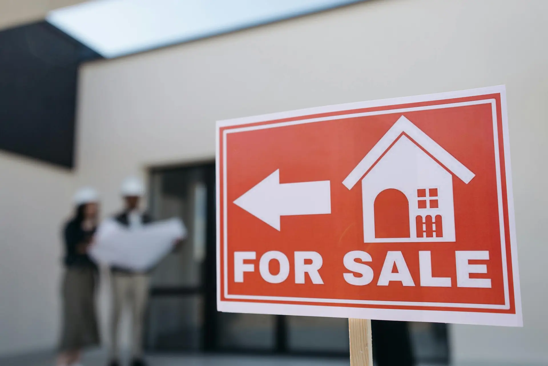 For sale sign with agents discussing plans